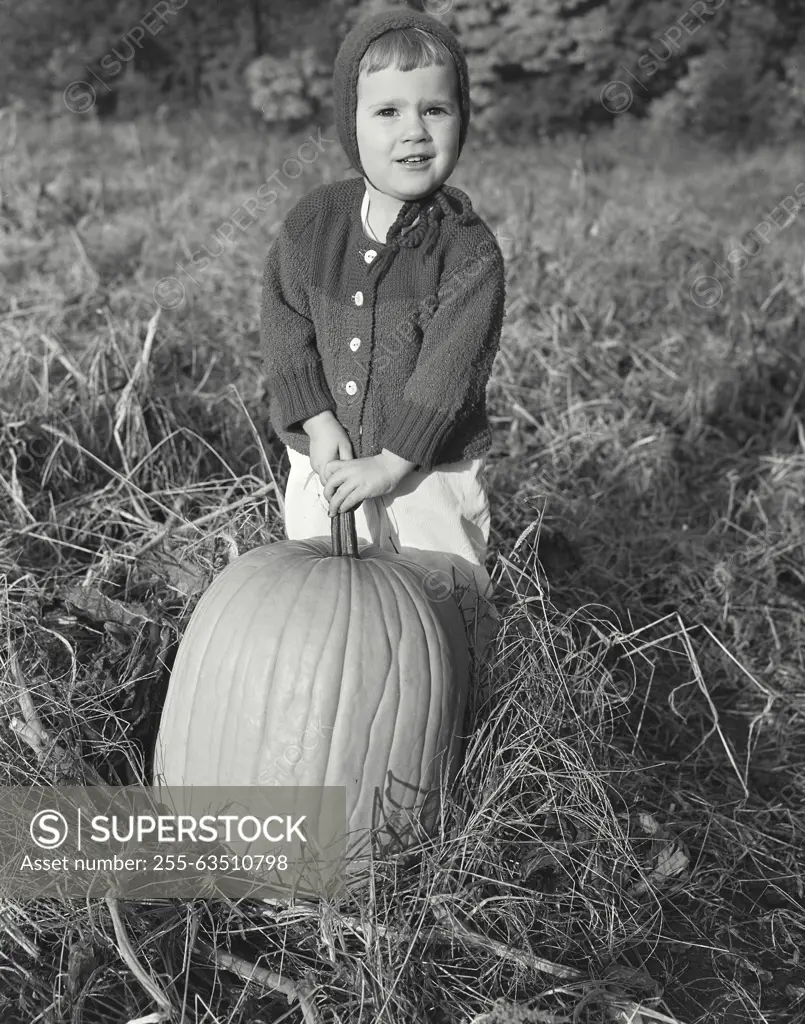 Model Release. Jodene Scaylea. Vintage Photograph. A little girl standing behind a large pumpkin.