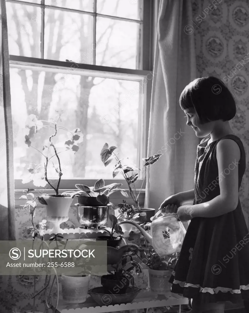 Little girl watering house plants