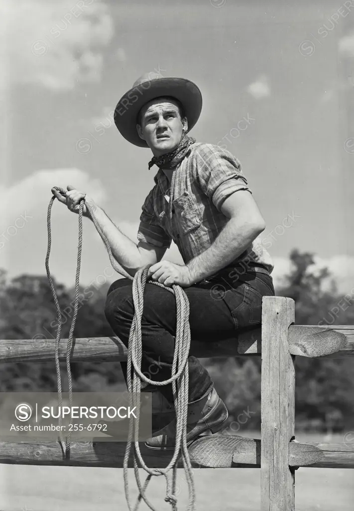 Vintage Photograph. Cowboy with rope sitting on fence. Frame 3