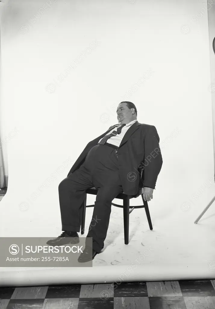 Vintage Photograph. Fat man resting in chair wearing suit jacket