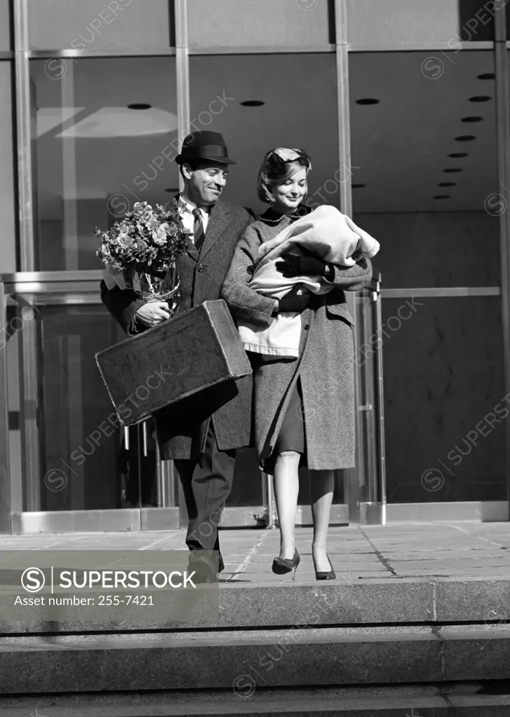 Happy couple leaving hospital with newborn baby