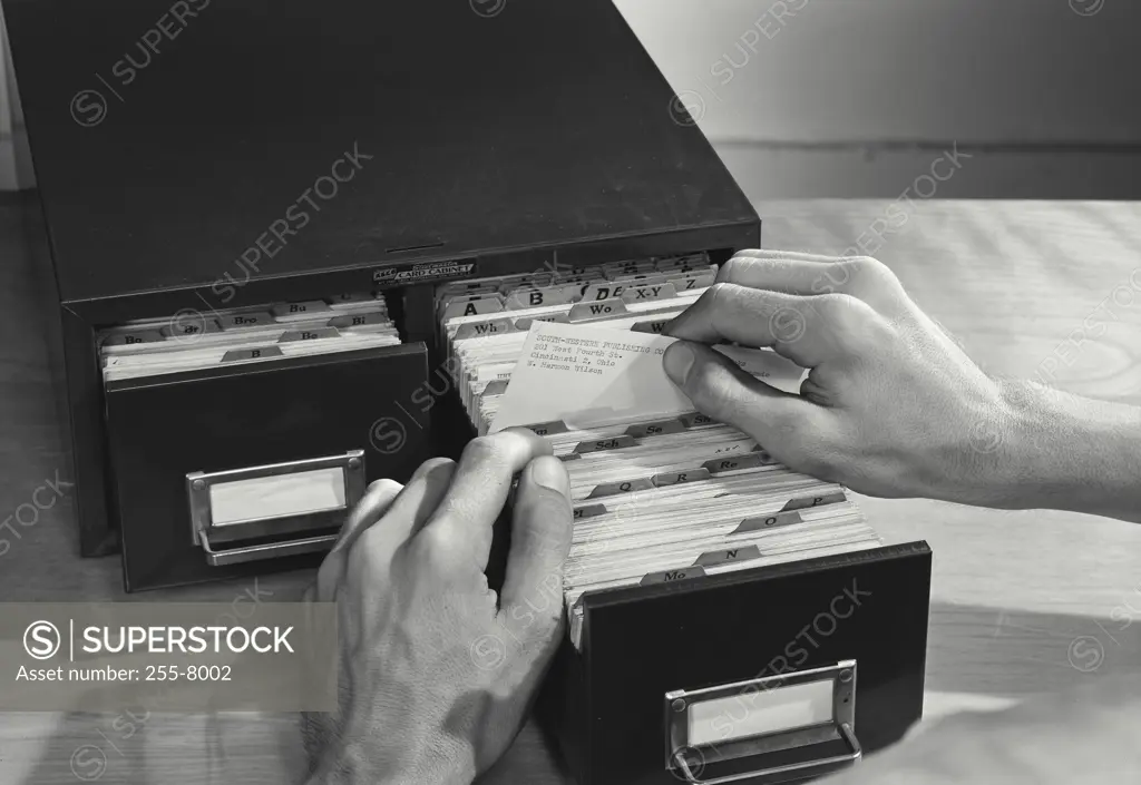 Vintage photograph. High angle view of a businessman filing cards in drawer