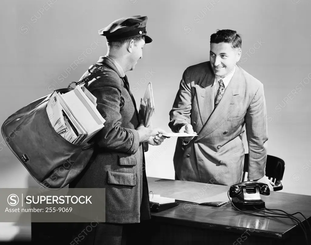 Side profile of a postman giving mail to a businessman