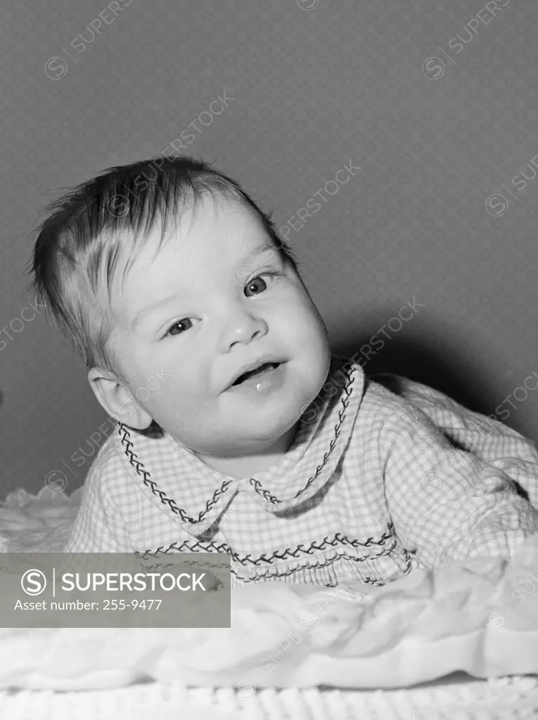 Portrait of smiling baby girl lying on front