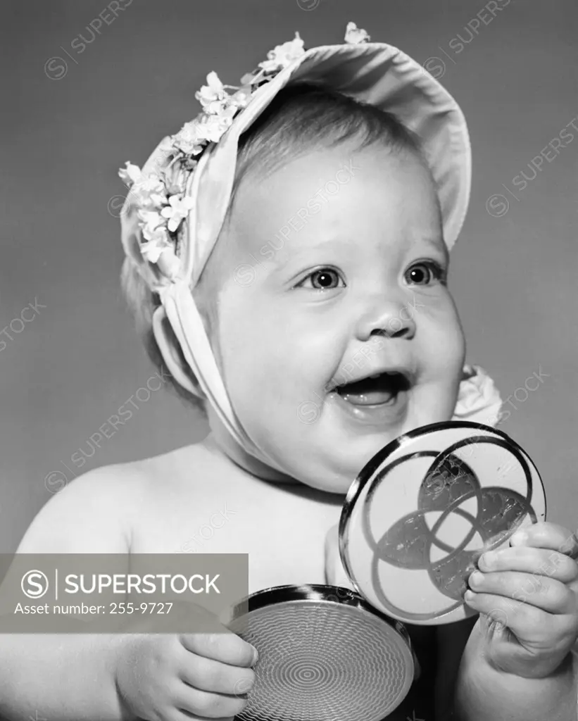 Portrait of baby girl holding hand mirror