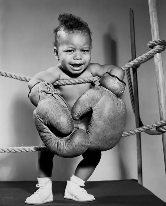 Crying baby wearing boxing gloves