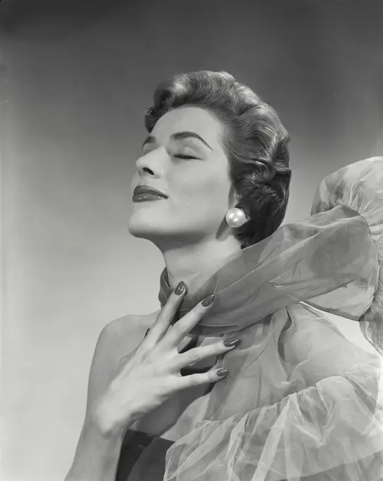 Vintage Photograph. Woman with short hairstyle smiling with eyes closed with wind blowing mesh scarf back