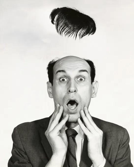 Toupe flying off of a surprised businessman's head