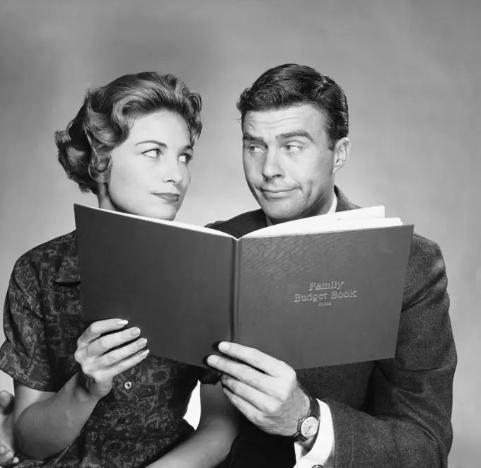 Close-up of a mid adult couple holding a family budget book