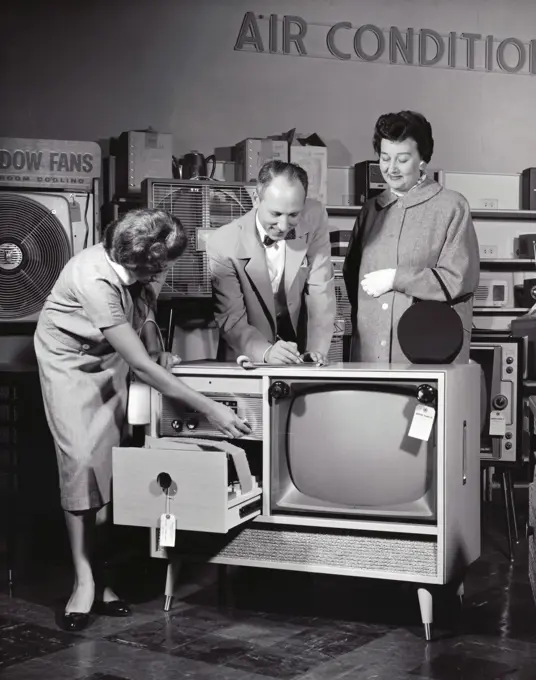 Female sales clerk showing a television set to a customer in an electronic shop