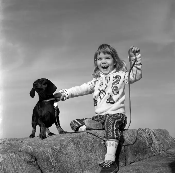 Girl with dog sitting on rock