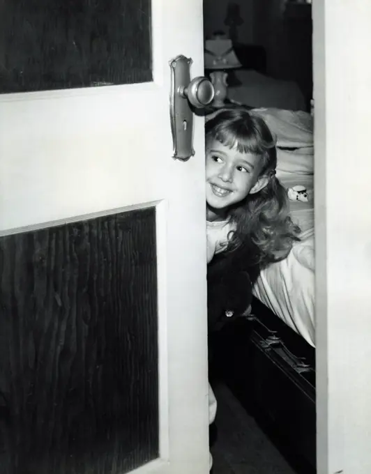 Girl peering around bedroom door