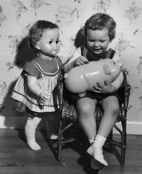 Little girl with piggy bank and doll