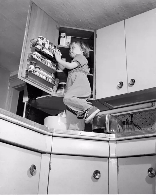 Girl standing on kitchen worktop, looking in cupboard