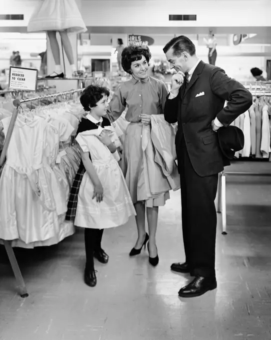 Girl selecting a dress in a clothing store with her parents