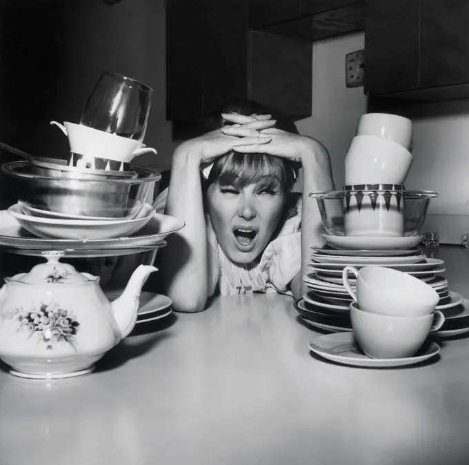 Young woman frustrated by stacks of dishes