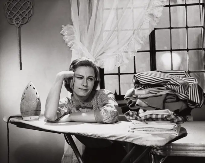 Young woman leaning on an ironing board