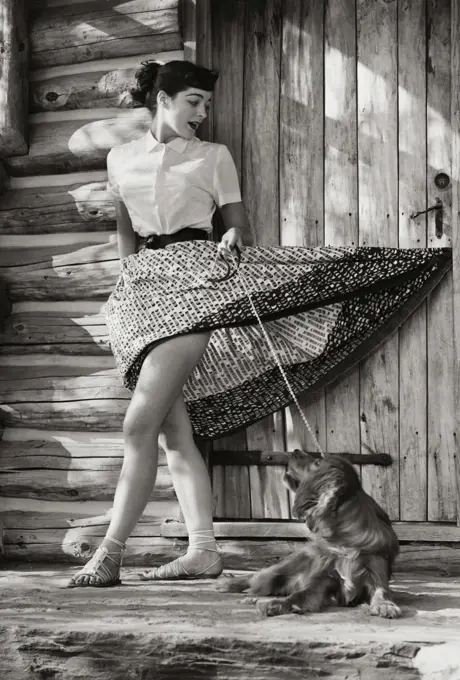 Young woman standing in front of her house with her dog