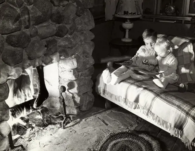 High angle view of two boys sitting on a couch and reading a book