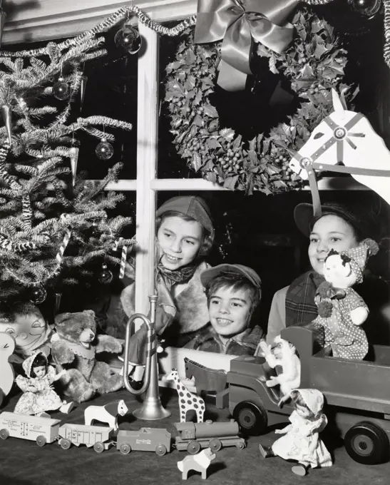 Two boys and their sister looking at toys in the display window of a toy store