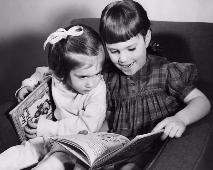 Older sister explaining picture book to younger sister