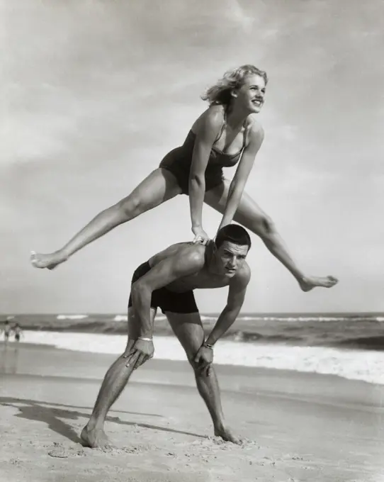 Young couple playing leapfrog on the beach