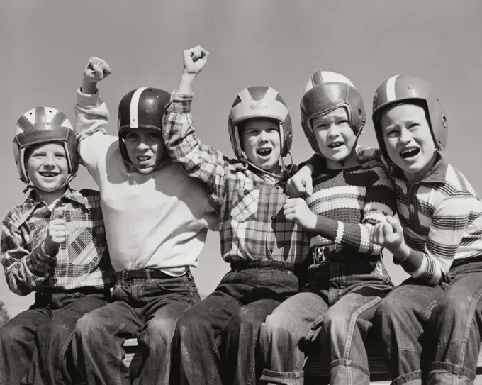 Five boys wearing sports helmets and cheering