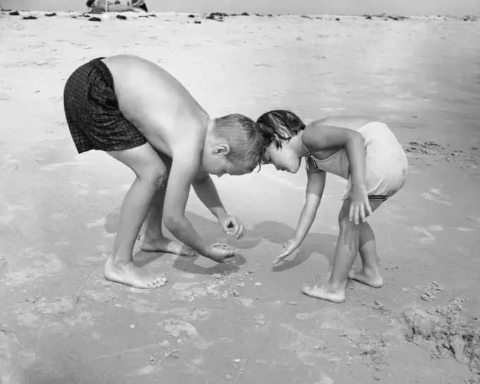 Boy with his sister collecting stones on the beach