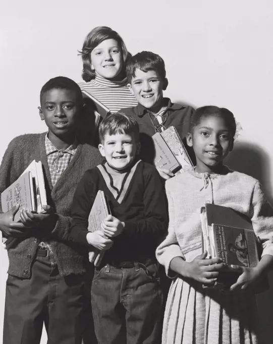 Schoolboys and schoolgirls holding books and smiling