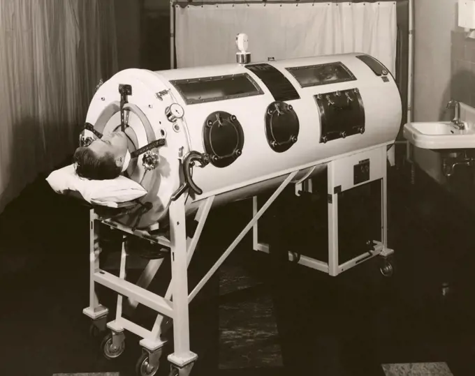 Mid adult man lying in an iron lung