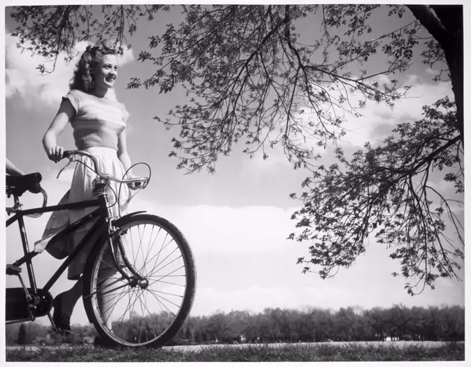 Low angle view of a teenage girl walking with a bicycle