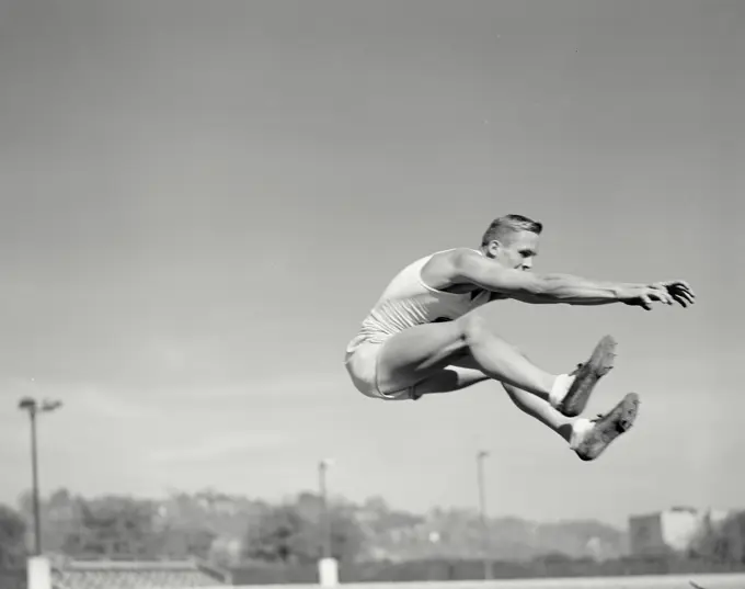 Vintage photograph. Runner in mid air for long jump.