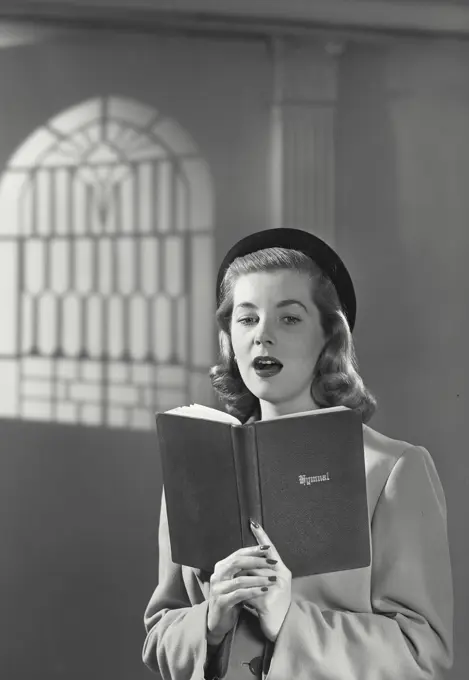 Vintage photograph. Close-up of a young woman in church reading from bible