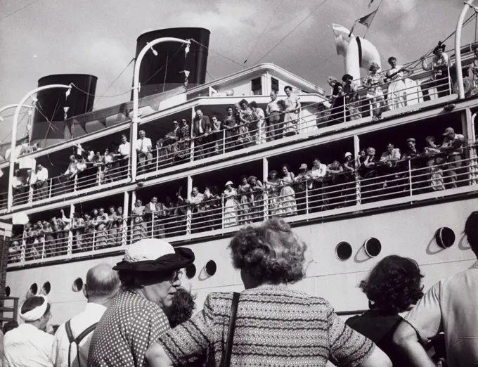 Group of people standing near a departing cruise ship