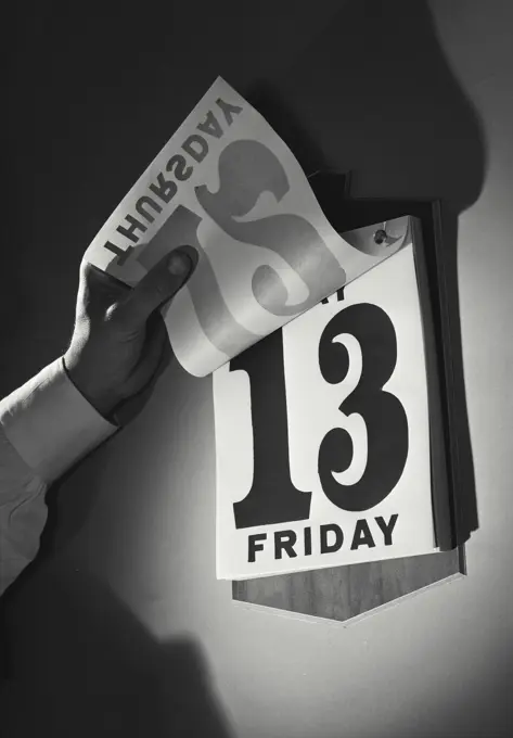 Vintage Photograph. Hand flipping up page on daily calendar to reveal Friday the 13th, Frame 1