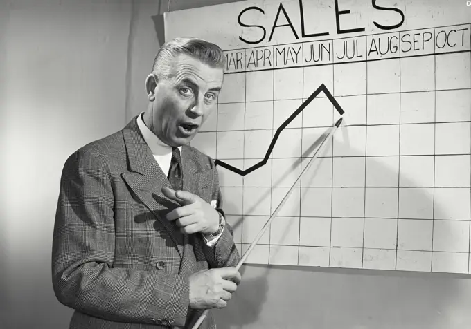 Vintage photograph. Businessman giving presentation in front of chart. Model released