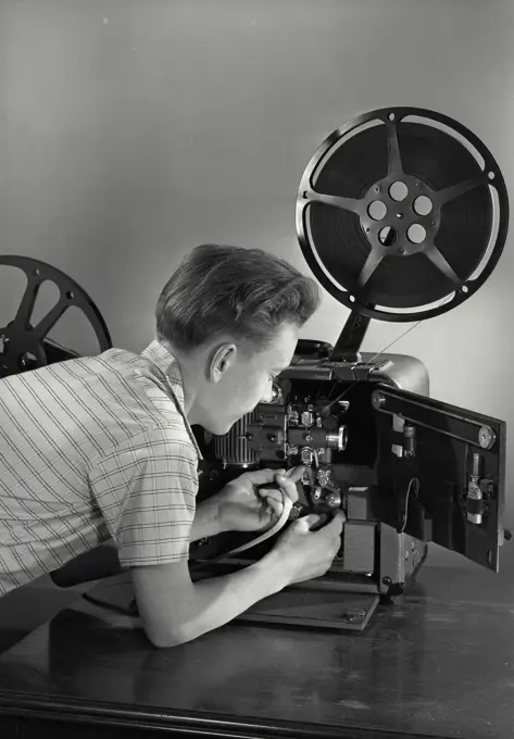 Vintage photograph. Young boy putting film in projector