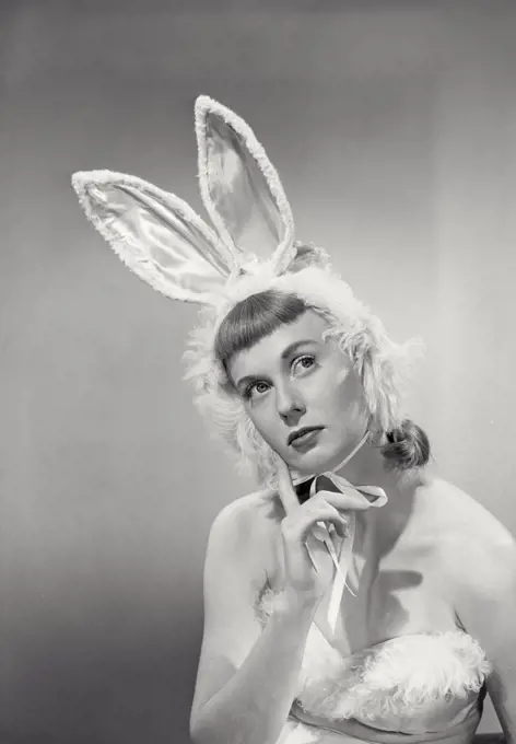 Vintage photograph. young woman wearing bunny ears with finger on chin