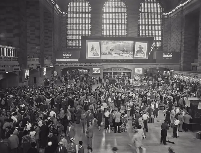 Vintage photograph. View looking at Kodak Exhibit sign behind crowd of people at a busy Grand Central Station.