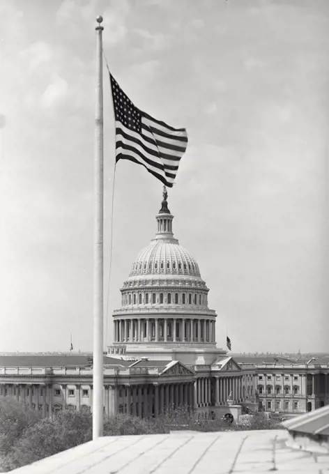 Vintage photograph. View of Capitol Building Rotunda in Washington DC with American Flag on pole in foreground