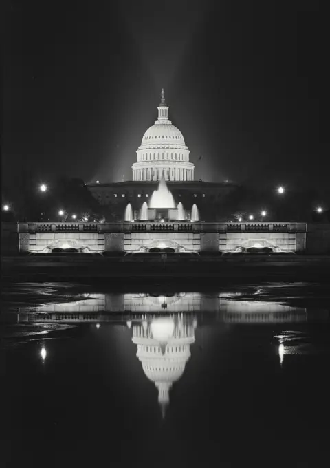 Vintage photograph. Capitol Building lit up at night in front of Capitol Reflecting Pool