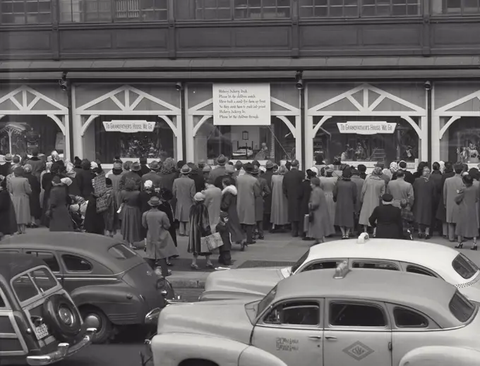 Vintage photograph. Christmas shoppers on sidewalk outside building looking in window, New York City