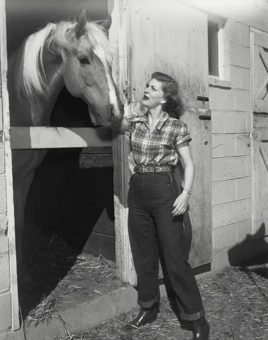 Vintage photograph. woman petting horse in stable