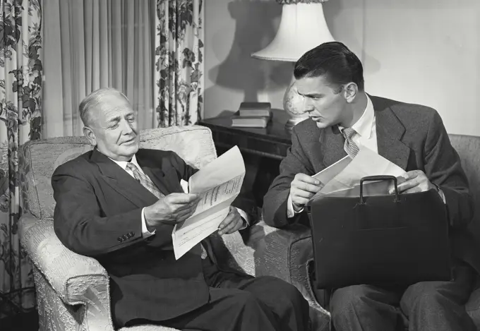 Vintage photograph. older man reading papers with young man