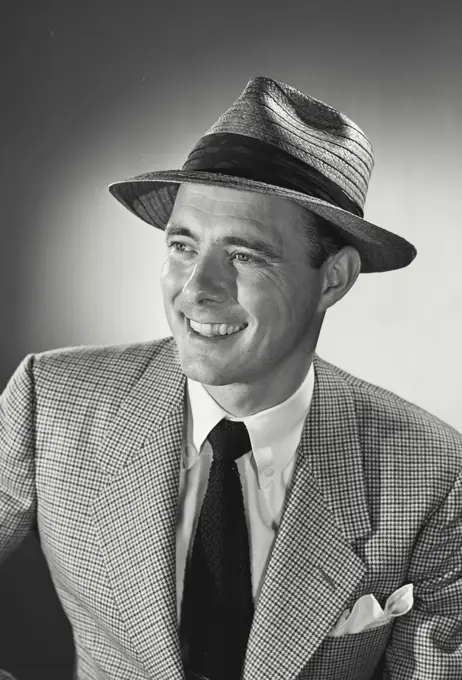 Vintage photograph. portrait of man in suit and tie smiling wearing hat.