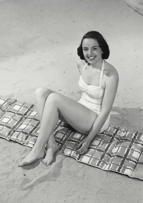 Vintage photograph. Woman in bikini sitting on beach