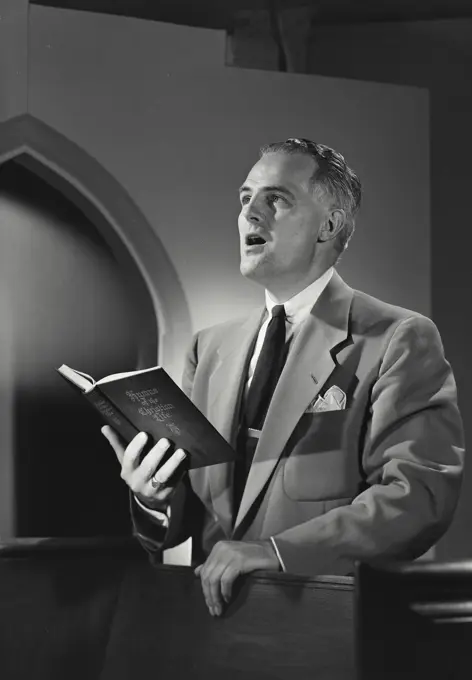 Vintage photograph. Man in church singing from Hymnal book