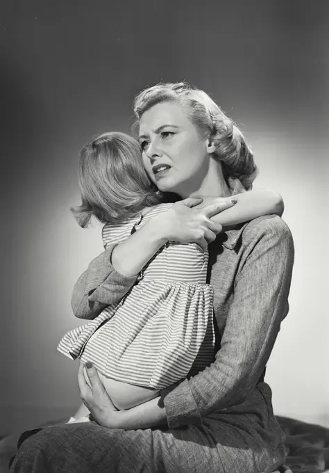 Vintage photograph. Mother hugging young daughter in lap with worried expression