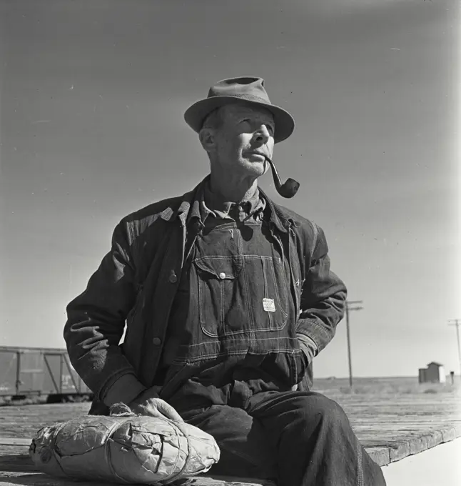 Vintage photograph. Portrait of farmer wearing overalls smoking pipe