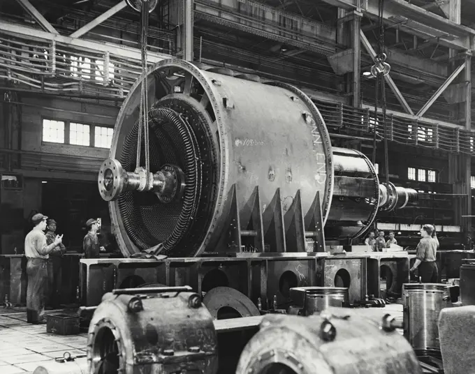 Vintage photograph. Threading a giant needle. Placing armature in stator housing. General electric co. Schenectady Works